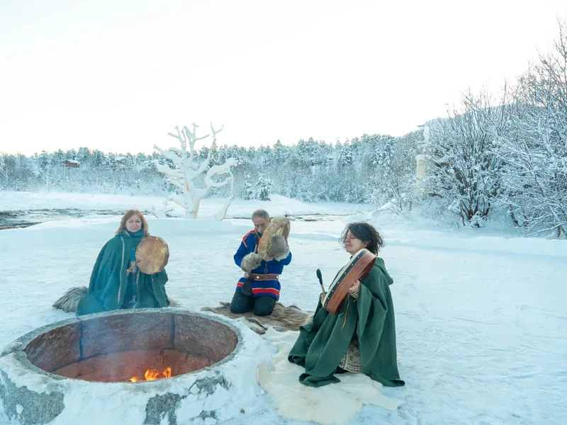 Guests in green cloaks around a hot tub in the snow
