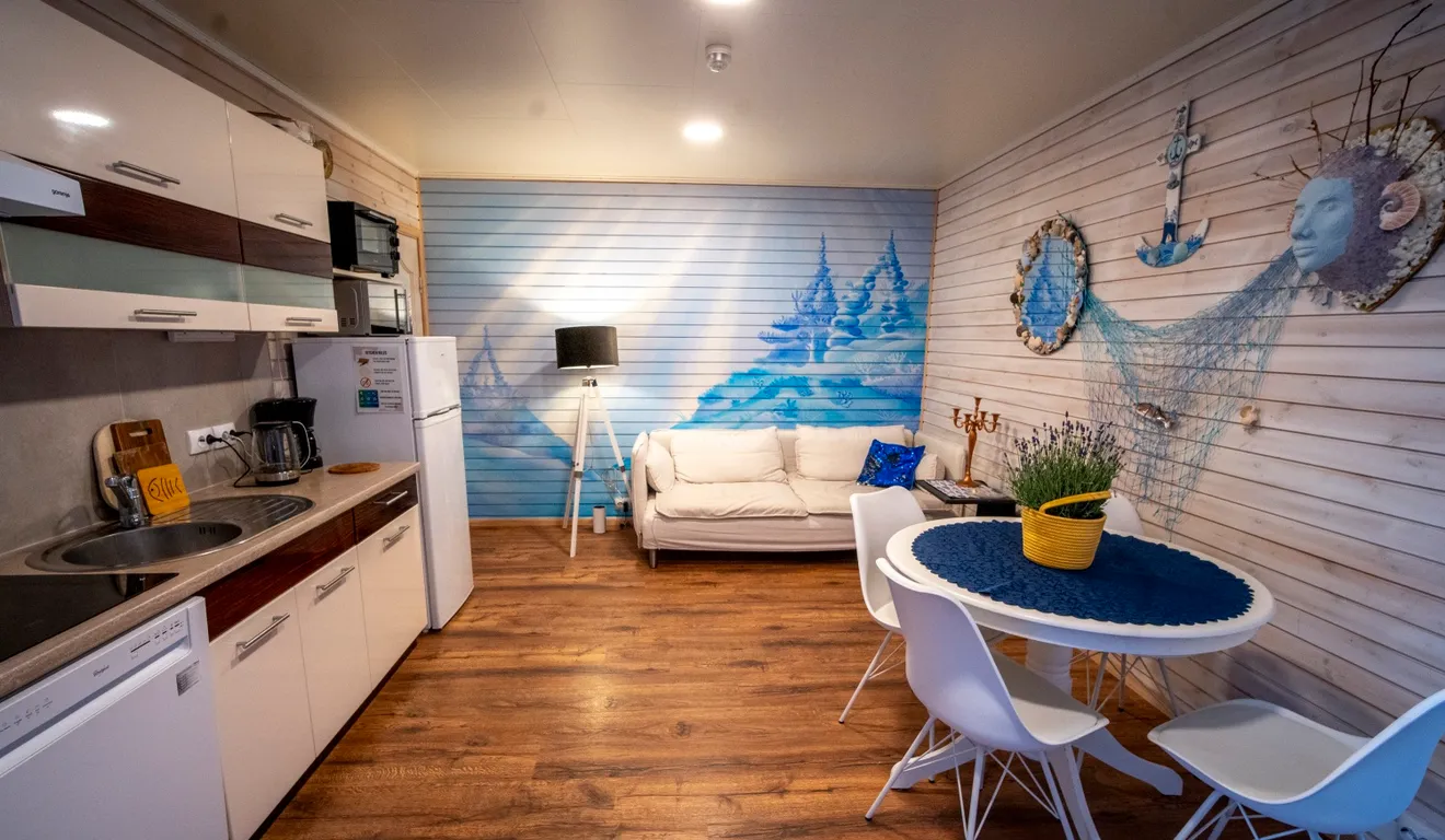 Living room with a sofa, round dining table and kitchen in the Havblikk apartment at Troll Havn, Vikran