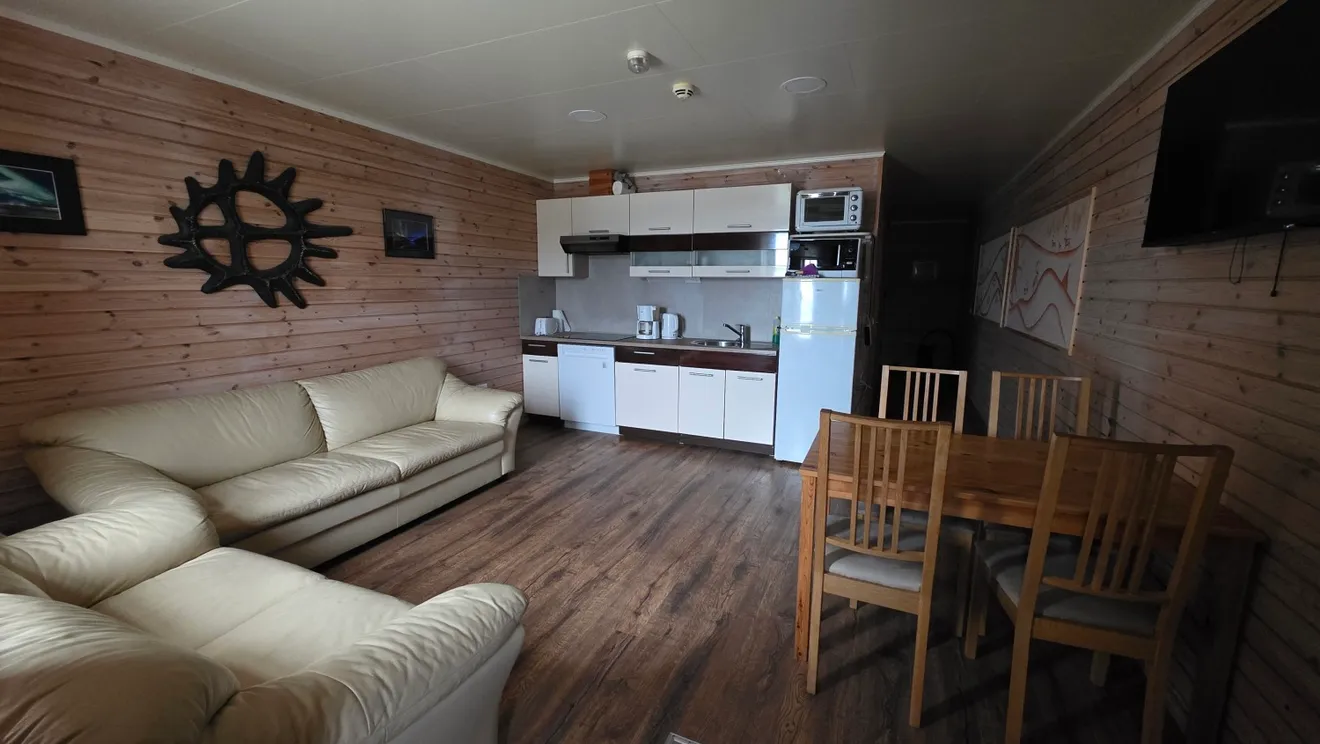 Living room with sofas, dining table and kitchen in the Nordlys apartment at Troll Havn, Vikran