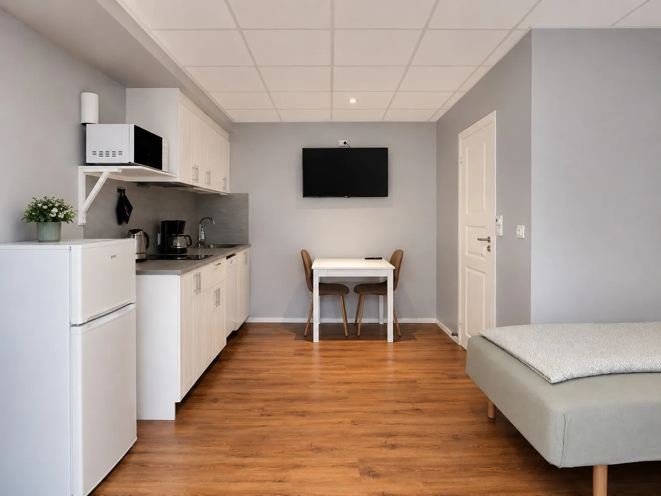 Kitchenette, dining table and a single bed in the Trollstua studio at Troll Havn, Vikran